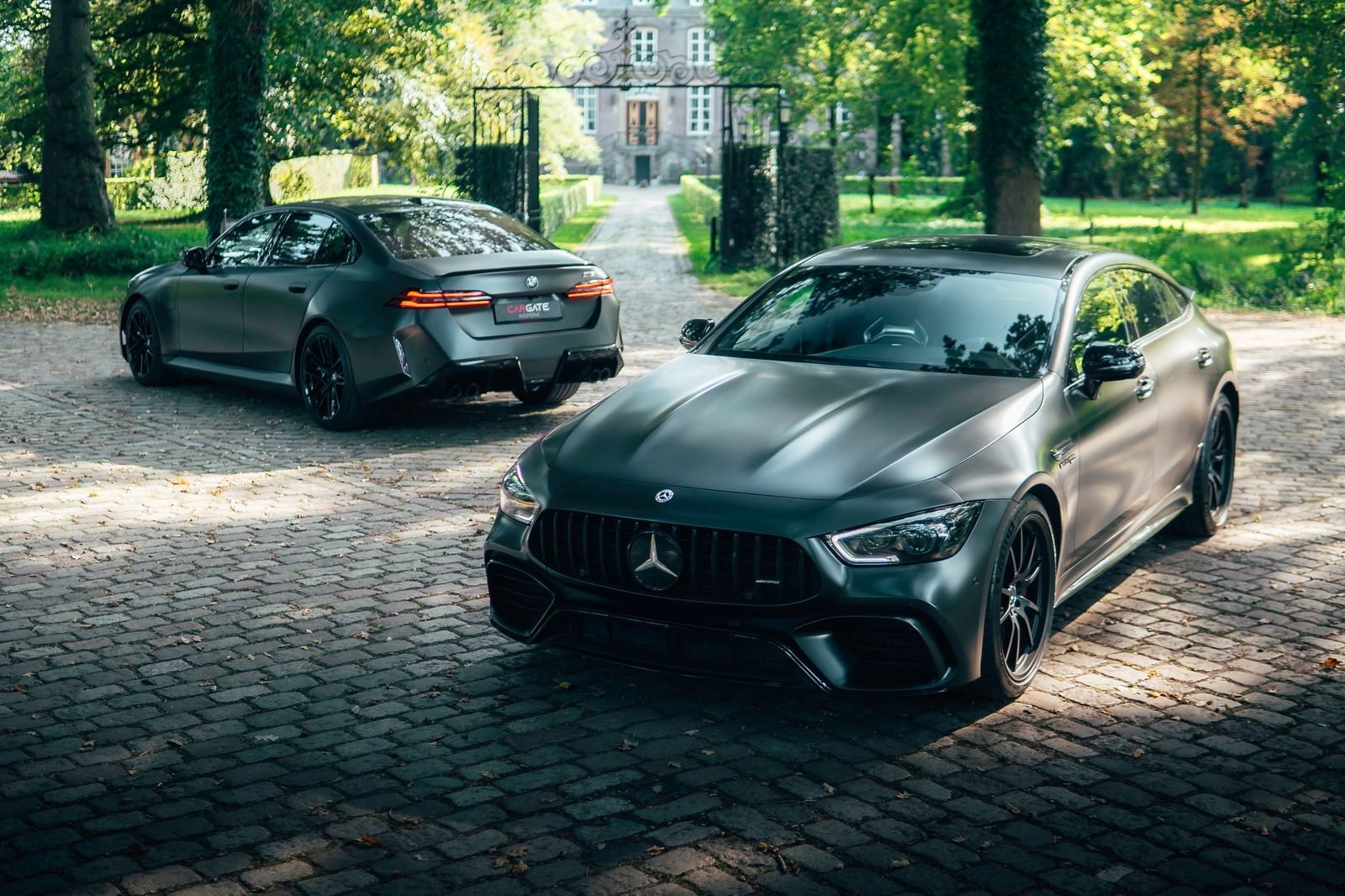 Twee zwarte sportauto’s op een oprijlaan bij een kasteel